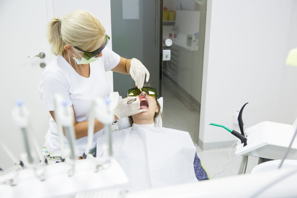 Dentist Performing Laser Dental Procedure - Laser Dentistry Dental professional using laser technology for a precise and minimally invasive dental procedure. - Laser Dentistry