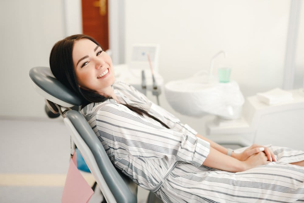 Smiling woman sitting comfortably in a dental chair, ready for a routine checkup and professional dental care. - Injections