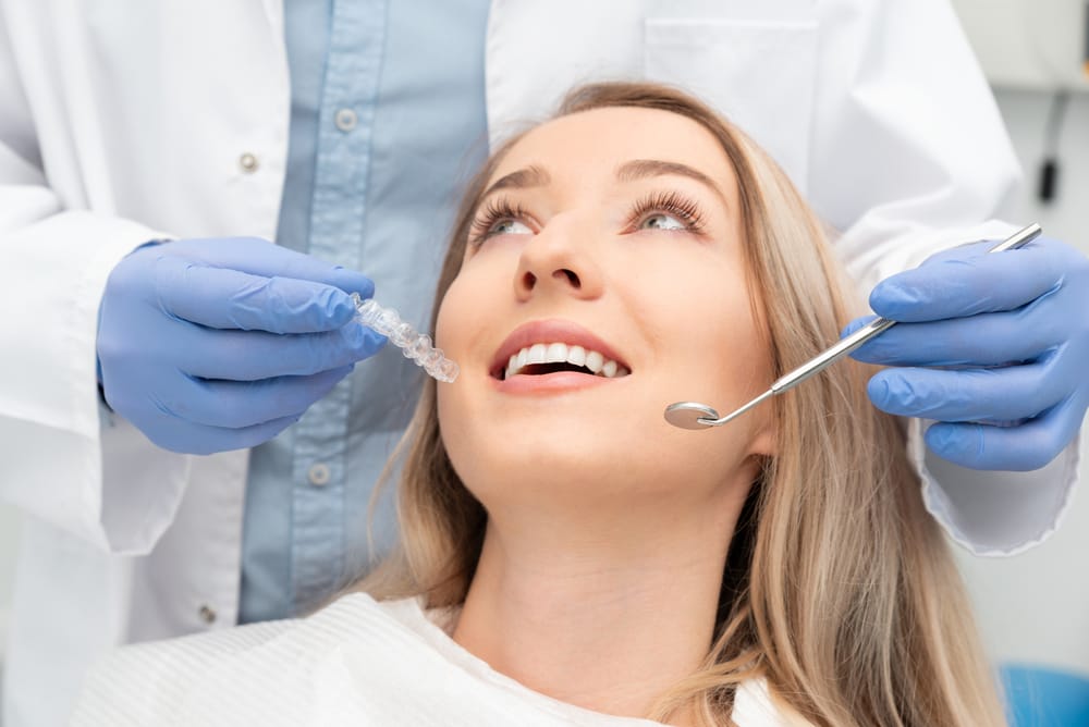 Dental professional presenting a clear aligner to a patient during an orthodontic consultation. - Sealants