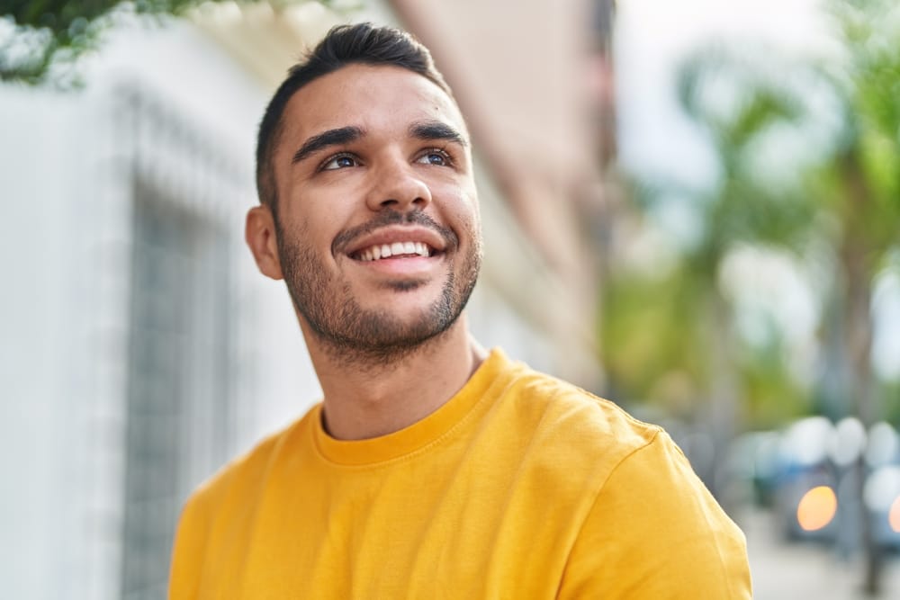 Happy young man smiling outdoors, symbolizing the benefits of restful and uninterrupted sleep. - Sleep Apnea 