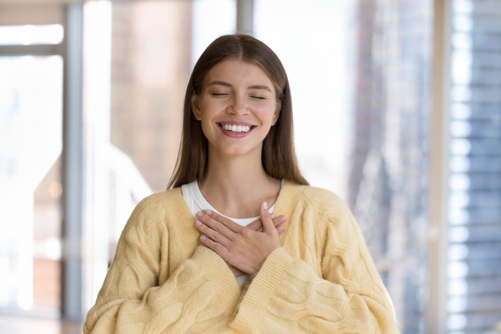 Woman Smiling with Gratitude After Dental Treatment - Laser Dentistry Happy woman with hands on her chest, expressing gratitude and joy after a successful dental care experience - Laser Dentistry